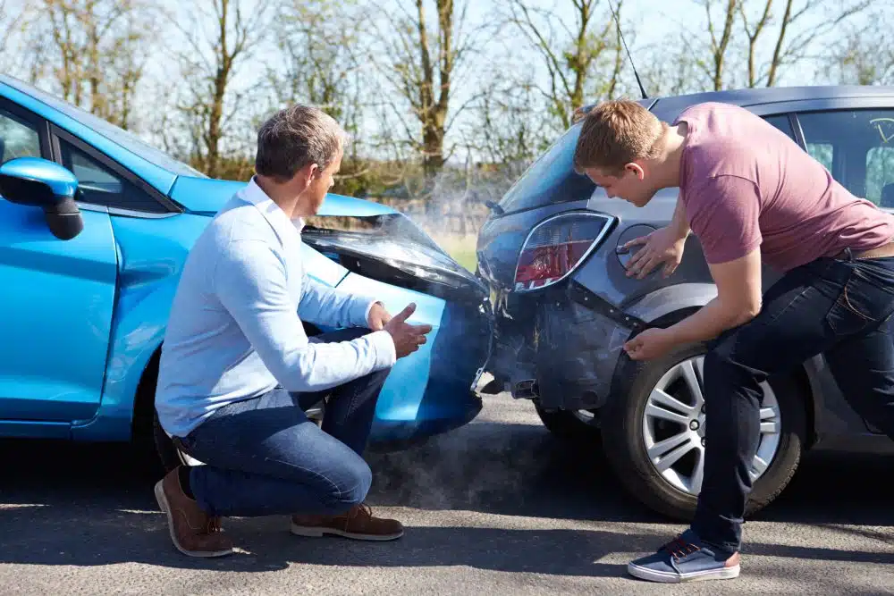 Two strangers in Fayetteville, Arkansas, inspect the damage of their vehicles after getting into a car accident.