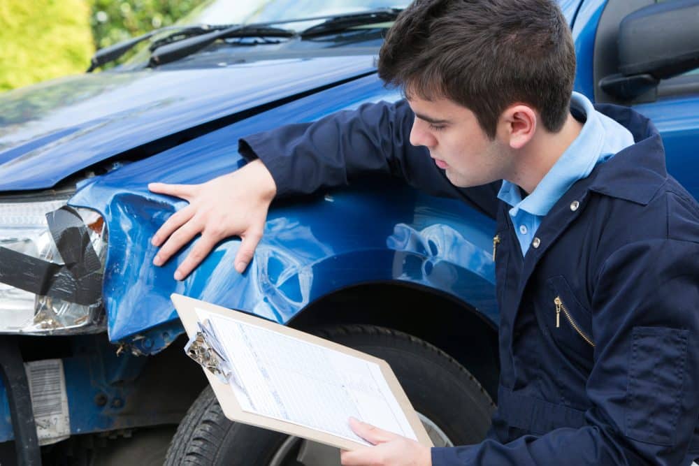 A mechanic inspecting the damage to a vehicle after a truck accident. 