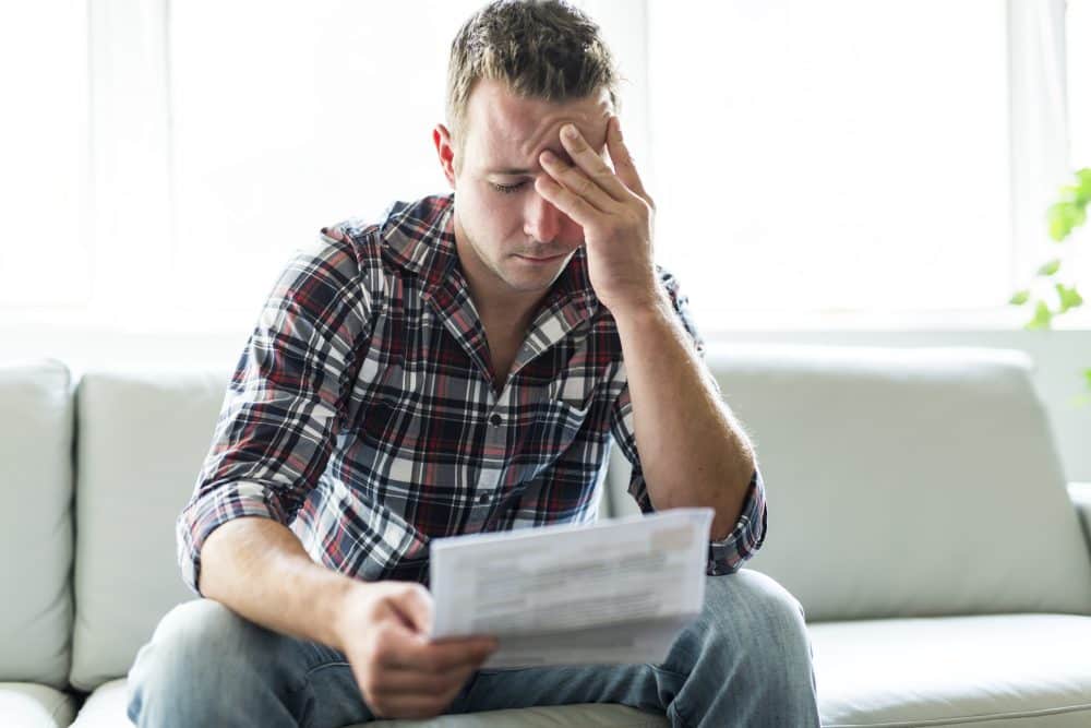 A man feeling stressed looking at bills after a personal injury.