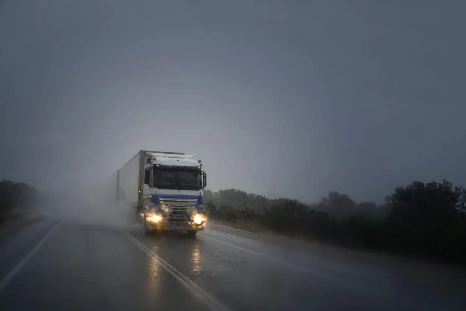 A commercial vehicle drives in the rain, increasing the risk of an Arkansas truck accident caused by bad weather.