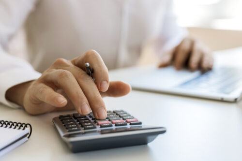 Someone calculating their personal injury settlement using a calculator and stack of documents.