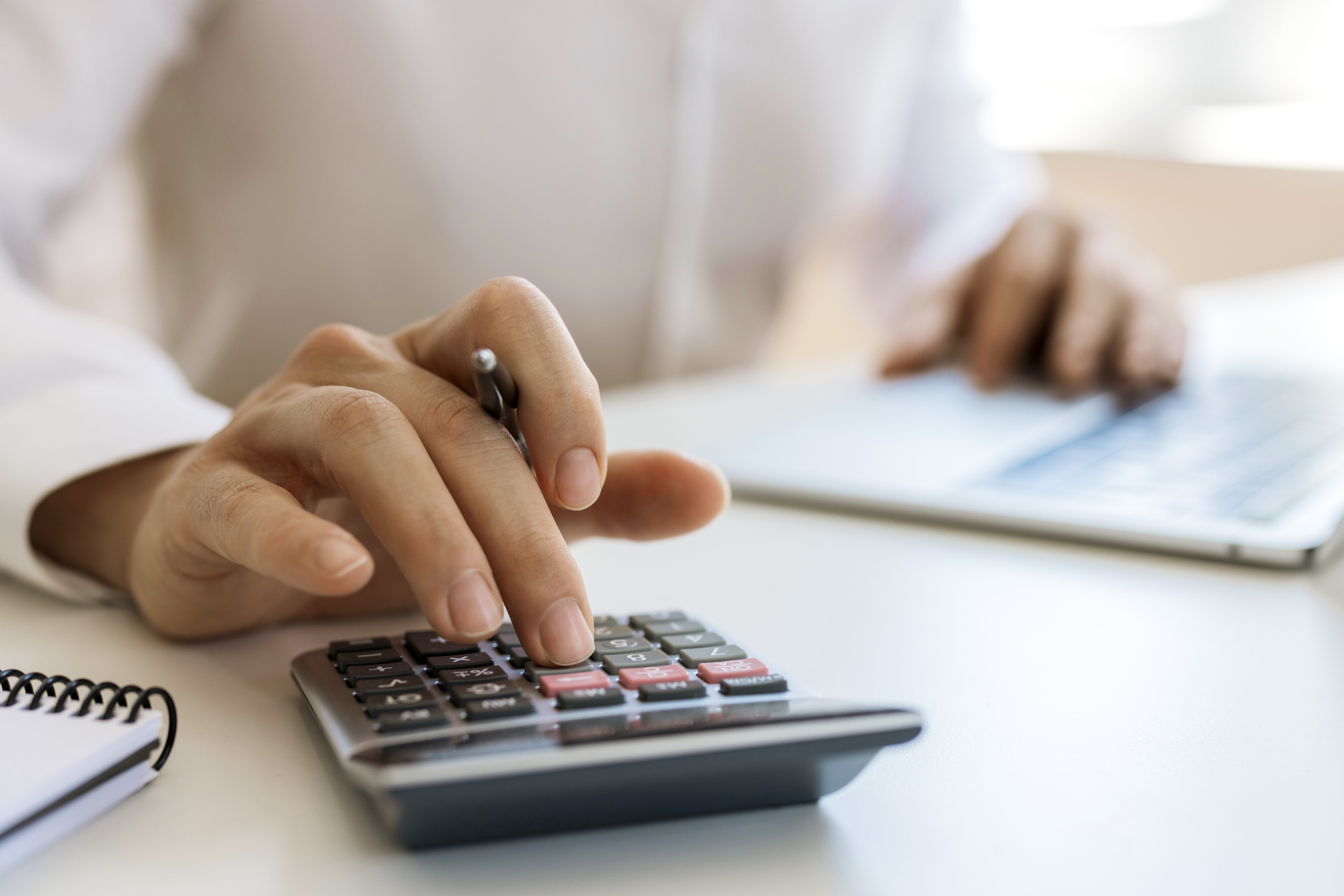 Someone calculating their personal injury settlement using a calculator and stack of documents.